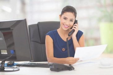 Woman on phone holding document at desk